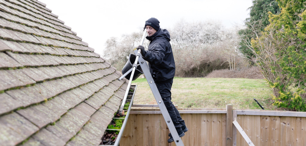 Technician manually clearing roof gutters 
